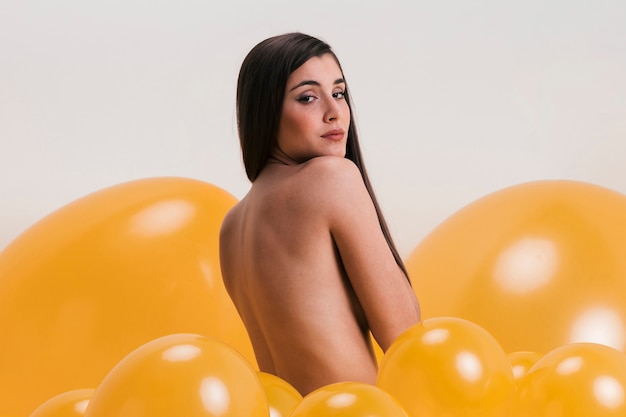 Donna nuda tra molti palloncini gialli