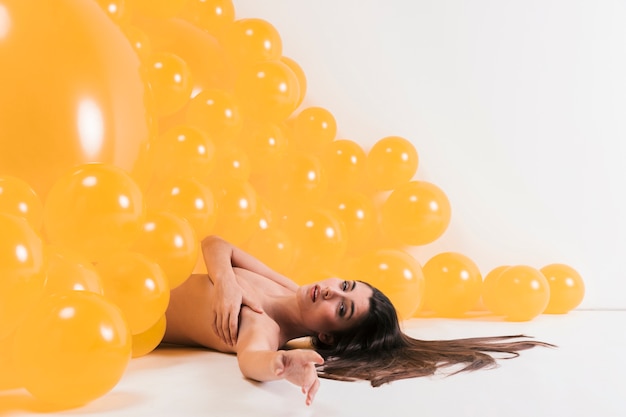 Donna nuda tra molti palloncini gialli