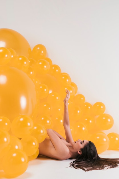 Donna nuda tra molti palloncini gialli