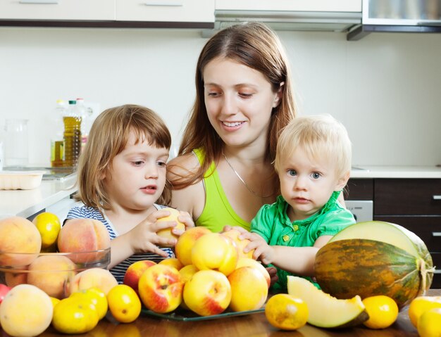 Donna ordinaria con le figlie che mangiano frutti