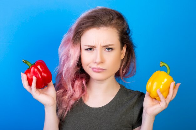 Donna perplessa che tiene i peperoni rossi e gialli in mani differenti