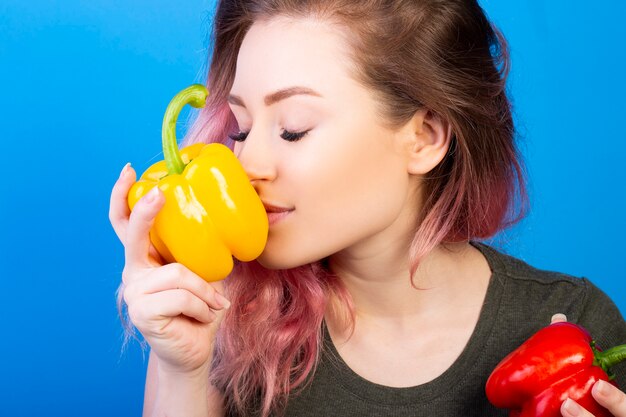 Donna piacevole che sente l'odore di un peperone giallo fresco in sua mano