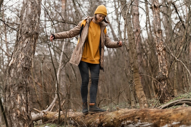 Donna piena del colpo che cammina sul ramo di un albero