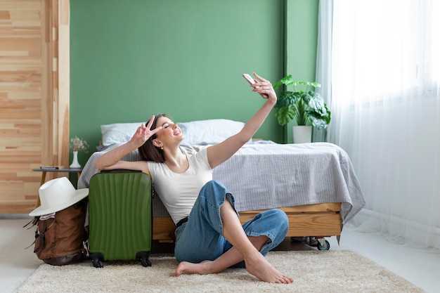 Donna piena del colpo che cattura selfie con i bagagli