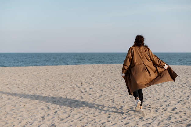 Donna piena del colpo che funziona sulla spiaggia