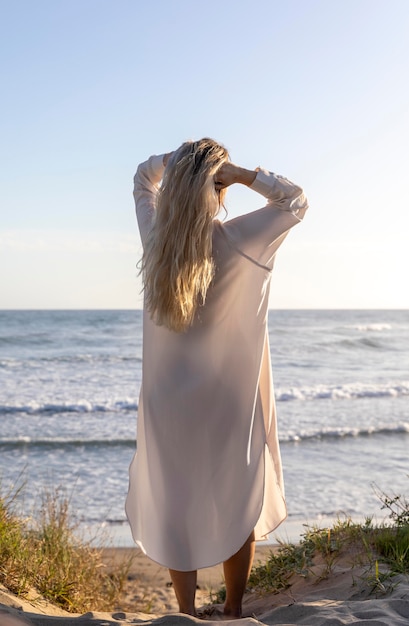 Donna piena del colpo che posa alla spiaggia