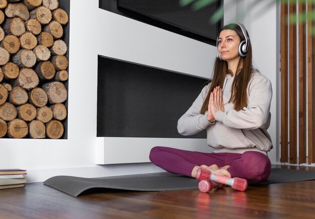 Donna piena del colpo che si siede sulla stuoia di yoga