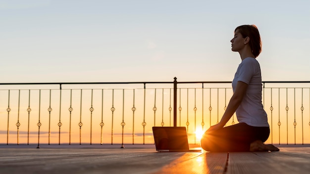 Donna piena del colpo con la meditazione del computer portatile