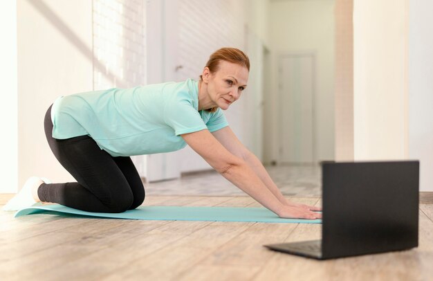 Donna piena del colpo sulla stuoia di yoga