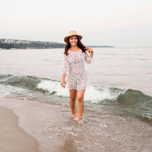 Donna piena di smiley del colpo che cammina sulla spiaggia