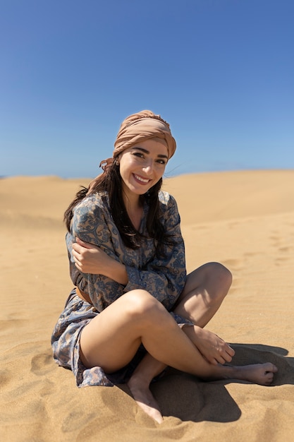 Donna piena di smiley del colpo che si siede sulla sabbia