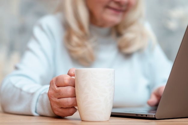 Donna più anziana del primo piano che per mezzo del computer portatile