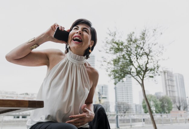 Donna più anziana di smiley che parla al telefono