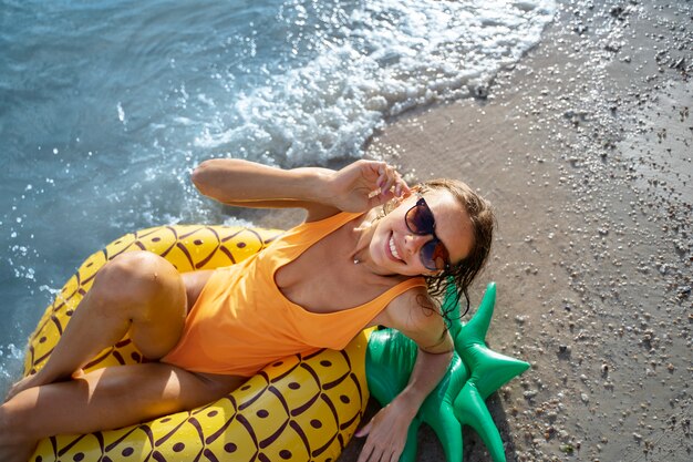 Donna posa sul galleggiante di ananas ad alto angolo