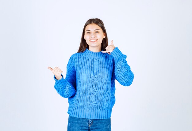 donna positiva in maglione blu in piedi su bianco.