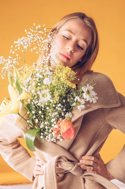 Donna premurosa con grande mazzo di fiori in cappotto