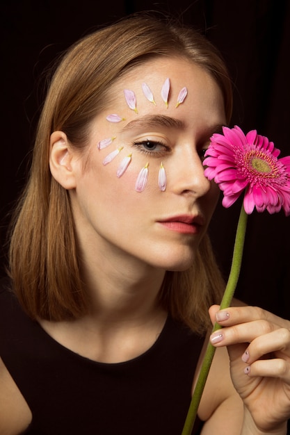 Donna premurosa con petali sul viso e gerbera