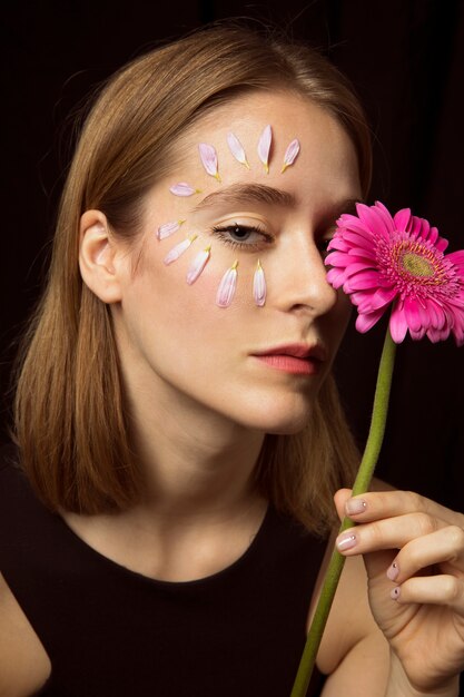 Donna premurosa con petali sul viso e gerbera