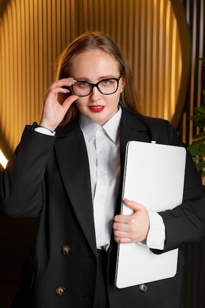Donna professionale in abito elegante in ufficio con il computer portatile