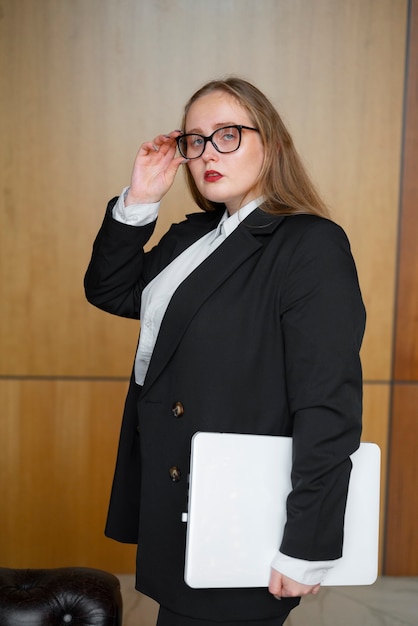 Donna professionale in abito elegante in ufficio con il computer portatile