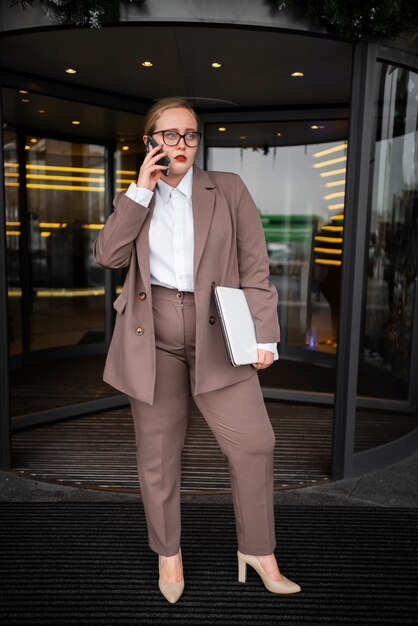 Donna professionale in abito elegante in ufficio con il computer portatile