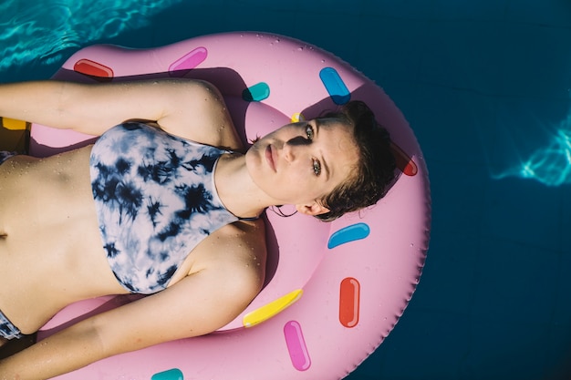 Donna raffreddando sul materasso gonfiabile in piscina