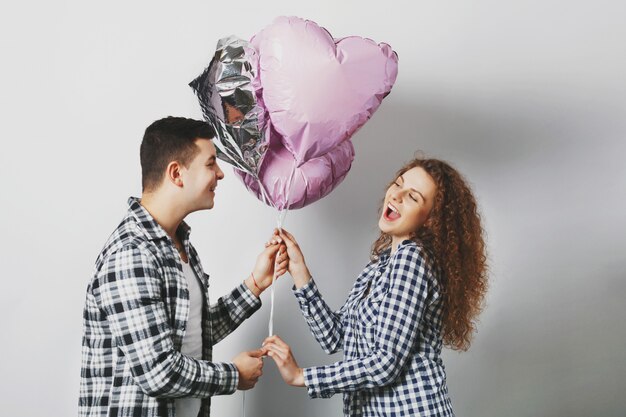 Donna riccia allegra sveglia felice di ricevere i palloncini del cuore dal ragazzo che è molto romantico