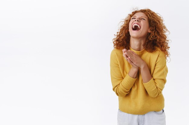 donna rossa felice con i capelli ricci, ridendo ad alta voce su bianco