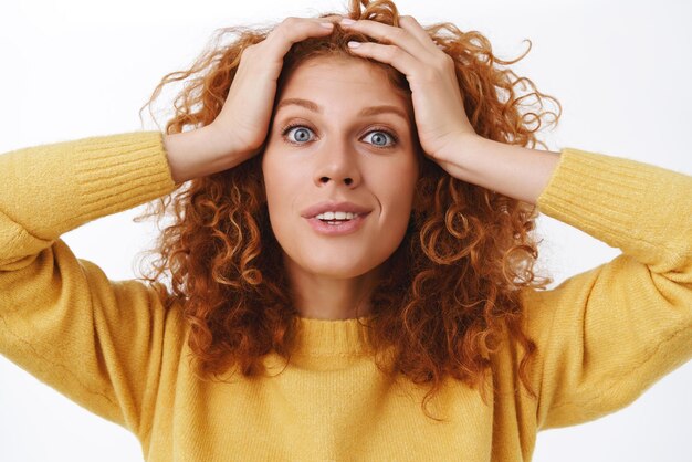 Donna rossa sorridente sorpresa del primo piano che si tiene per mano sui capelli ricci e che guarda la telecamera con un sorriso sbalordito deliziato non riesco a credere di aver vinto ancora fissando incredulità mentre riceve una buona notizia confortante