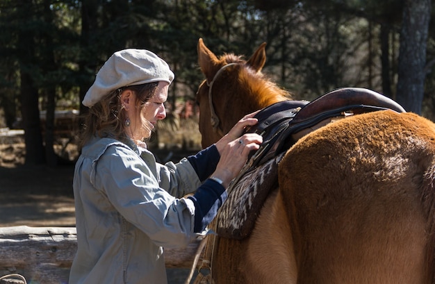 Donna rurale che sella il suo cavallo nel campo