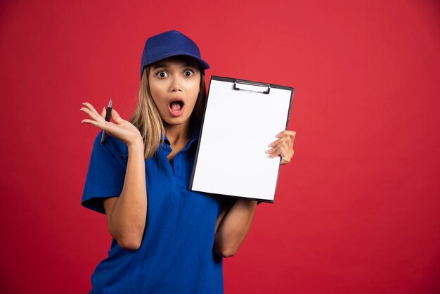 Donna scioccata in uniforme blu che tiene appunti con la matita.