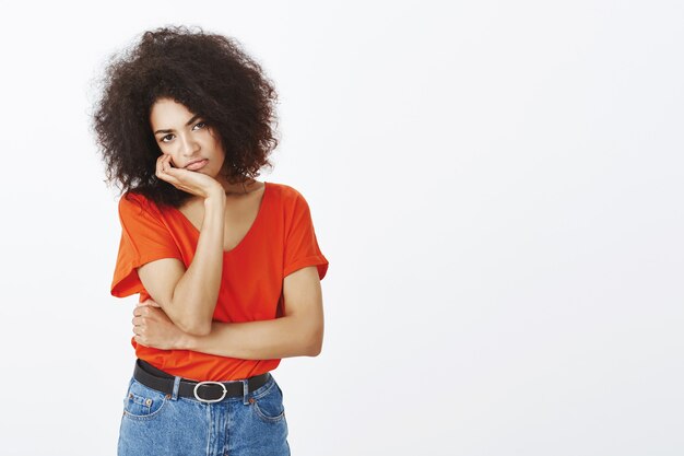 donna scontenta con acconciatura afro in posa in studio