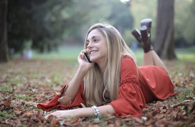 Donna sdraiata sul suolo della foresta e parlando al telefono