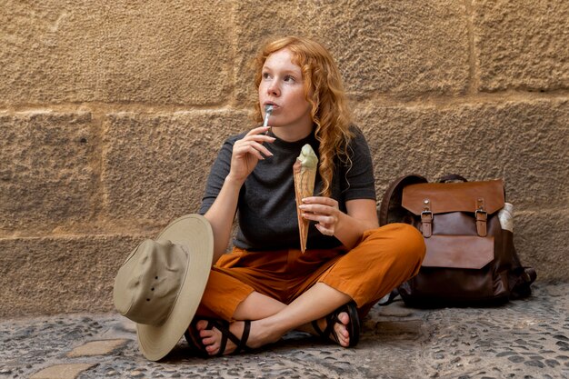 Donna seduta a terra e mangia il cono gelato