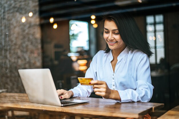 donna seduta con un computer portatile e pagato con una carta di credito in un bar