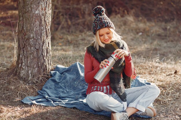 donna seduta da un albero in una foresta di primavera con un drink thermos