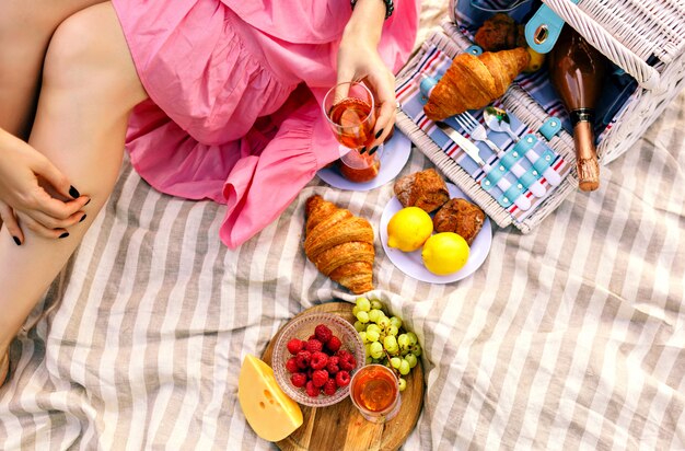 Donna seduta e tenendo un bicchiere di champagne, frutta tradizionale, croissant e formaggio,