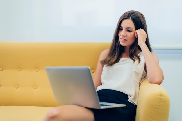 Donna seduta su un divano con un computer portatile sulle gambe