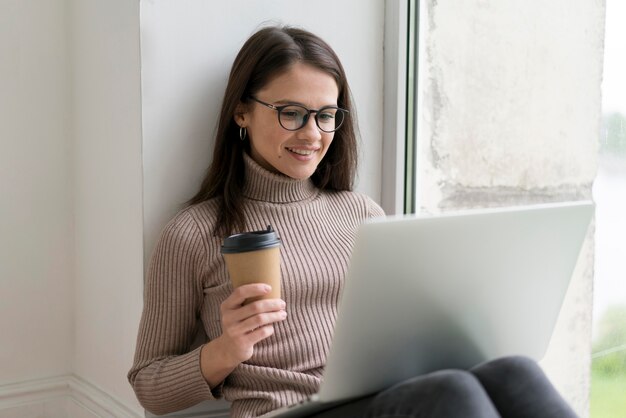 Donna seduta sul pavimento che lavora al suo laptop