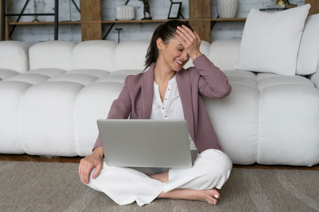 Donna seduta sul pavimento con un laptop in grembo