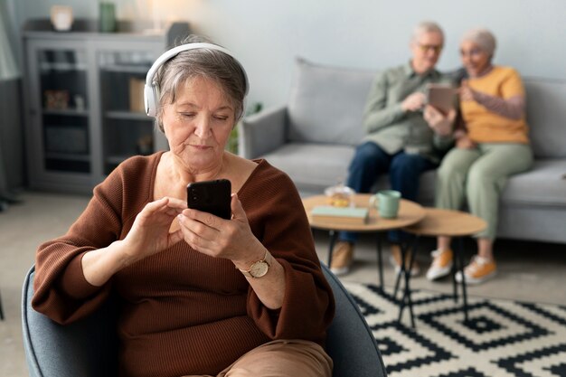 Donna senior che ascolta la musica che si siede nel salone a casa