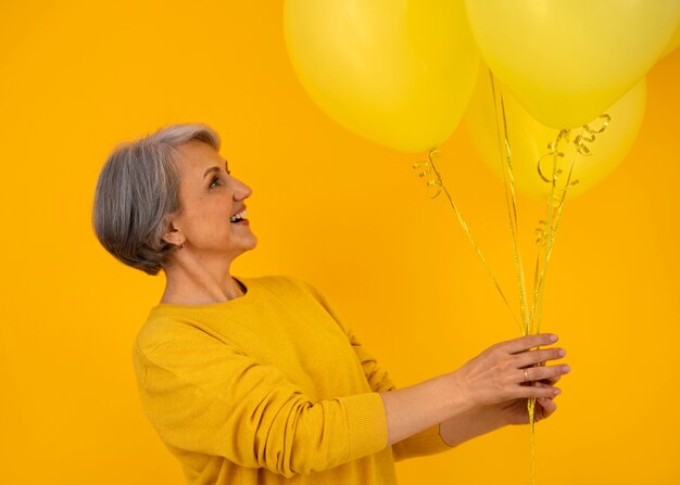 Donna senior del colpo medio che posa con gli aerostati