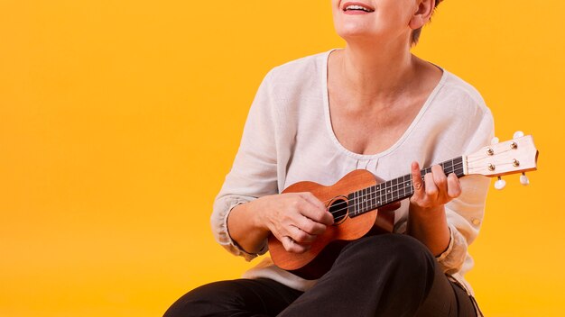 Donna senior del primo piano che gioca chitarra