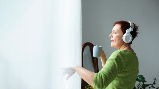 Donna senior dello Copia-spazio che canta alla tazza