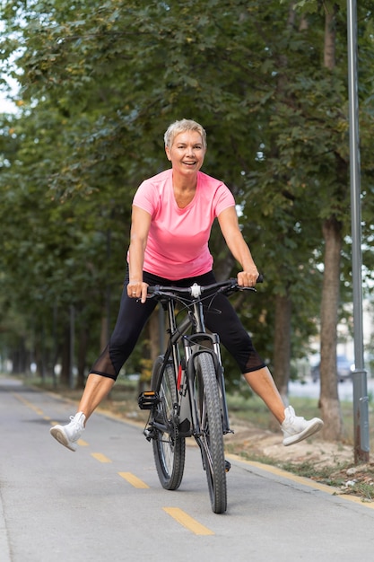 Donna senior di smiley che si diverte a guidare la bici all'aperto