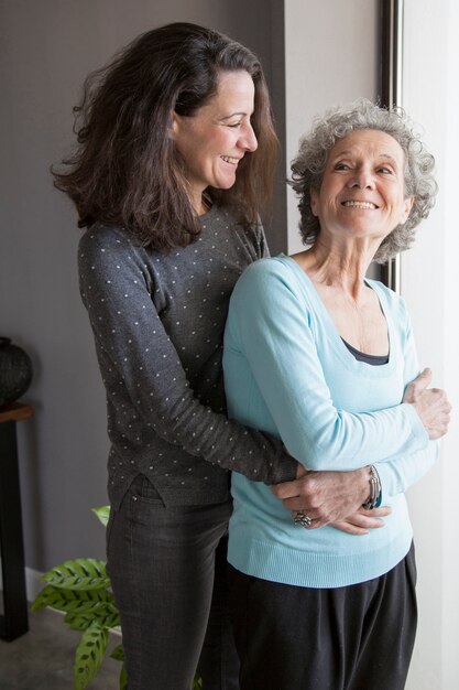 Donna senior eccitata allegra abbracciata dalla figlia che gira indietro