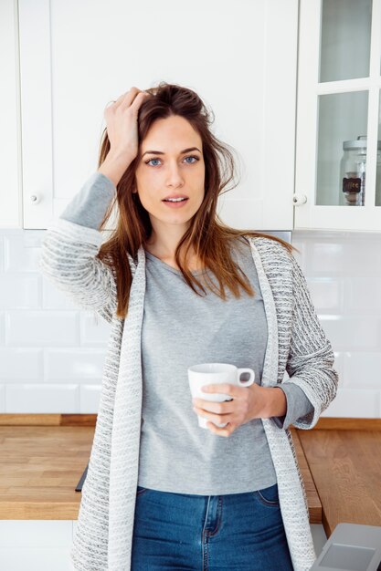 Donna sensuale con la tazza in cucina