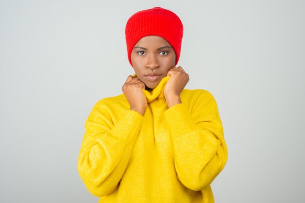 Donna seria che porta maglione giallo brillante e cappello rosso