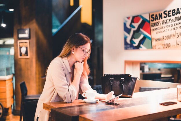 Donna seria che utilizza smartphone nel caffè