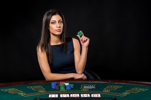 Donna sexy con carte da poker e fiches. Giocatrice in un bellissimo vestito nero